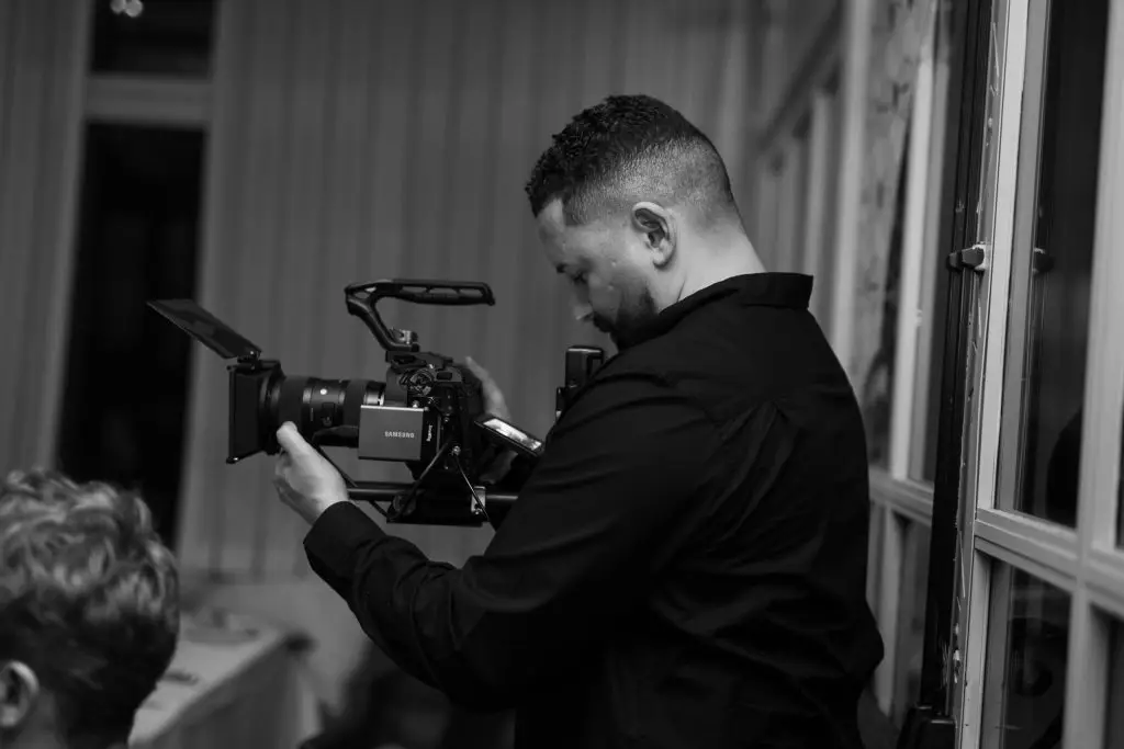 Black and white photograph of Luis Rivera operating a cinema camera